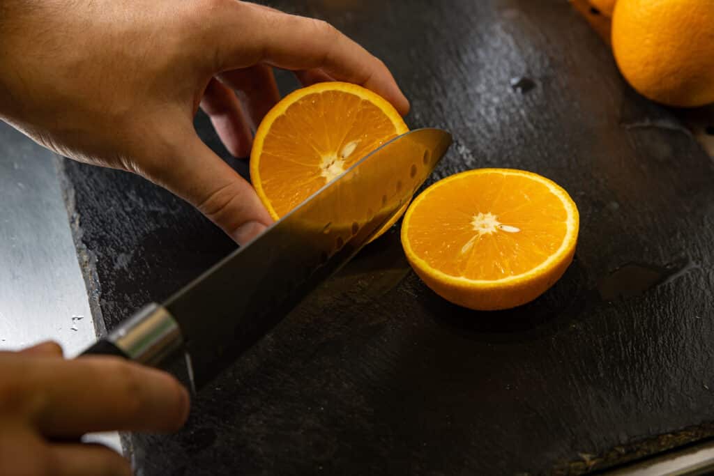Person slicing an orange to use orange oil treatment for termites in riverside ca home