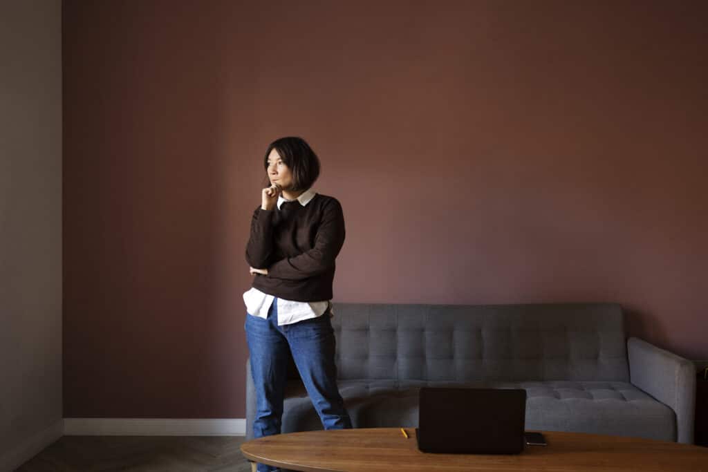 woman homeowner standing in front room hearing chewing in the walls wondering if its roof rats